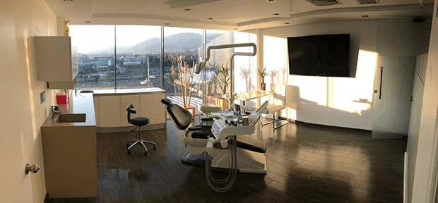 Odontólogo especialista revisando a paciente en sillón dental moderno dentro de una clínica privada en Lo Barnechea, Chile
