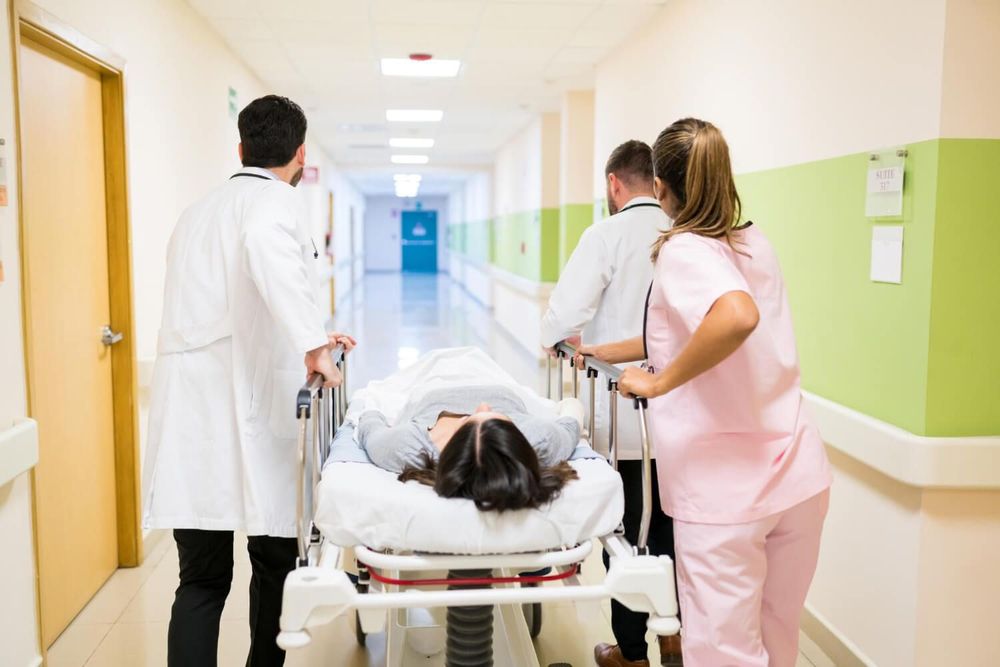 Equipo médico traslada a una paciente en camilla por el pasillo de un hospital